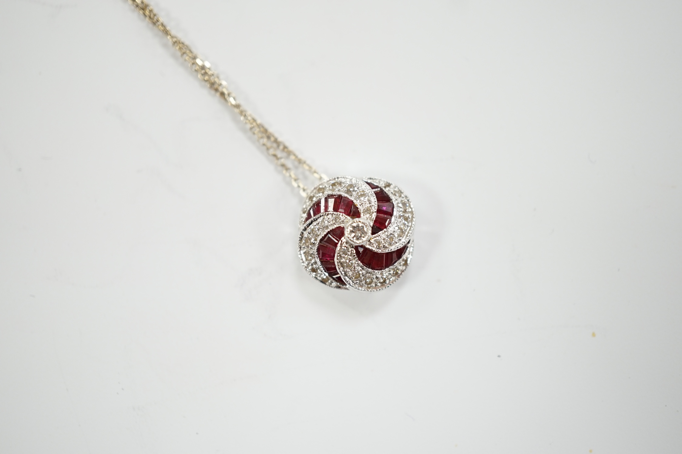 A modern 18ct white gold, ruby and diamond cluster set pendant, 14mm, on a 750 white metal fine link chain, 39cm, gross weight 3.4 grams.